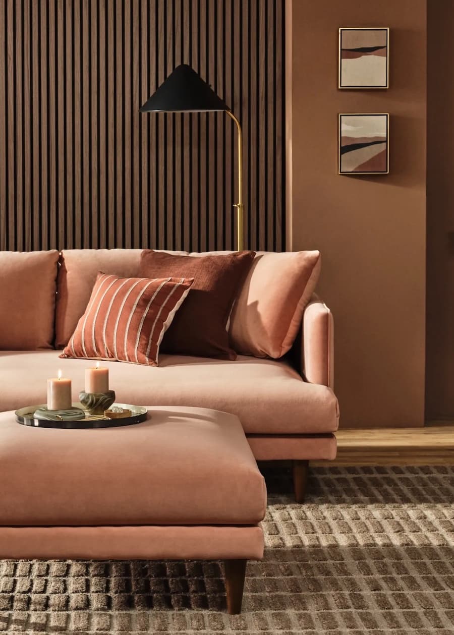 Living moderno con el color Pantone 2025, Mocha Mousse. Sofá bajo color café claro. mesa de centro acolchada y muros con revestimiento de madera café.