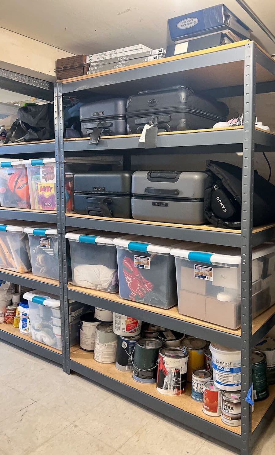 Estante de una bodega con distintas maletas y cajas plásticas organizadoras transparentes.