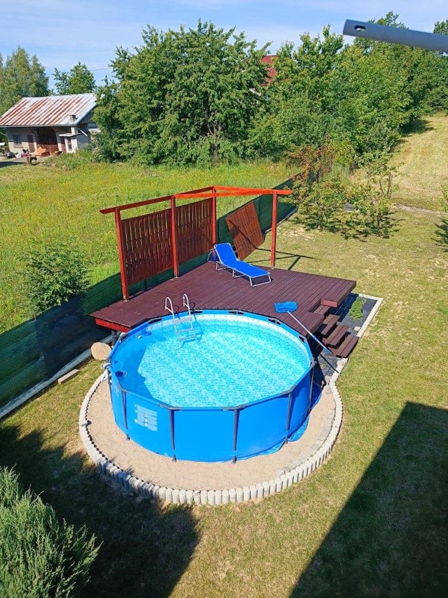 Vista aérea de un patio con piscina estructural redonda. Junto a ella hay un deck de madera con una reposera azul