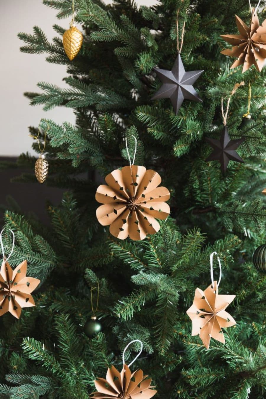 Árbol de Navidad con adornos en forma de flor y estrellas, hechos con papel kraft.
