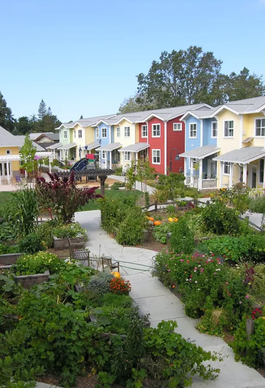 Conjunto de casas de diferentes colores con un gran jardín central con árboles y jardines