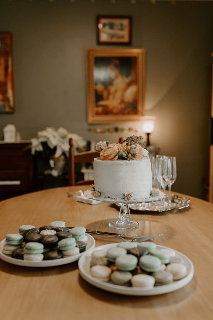 Torta de matrimonio blanco en una mesa de un comedor. También hay plato con otros aperitivos y una bandeja con copas de champaña.