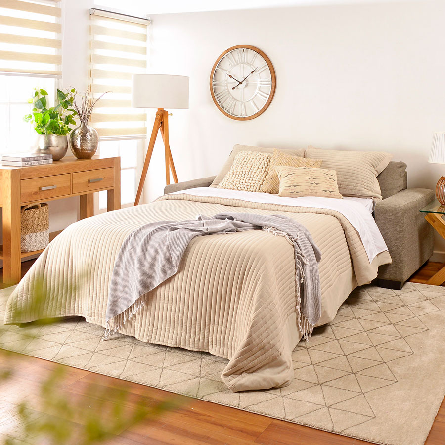 Dormitorio con sofá cama gris con ropa de cama beige