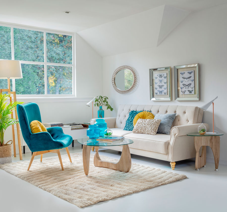 Living en colores claros, con sofa color crudo y alfombra cruda. Poltrona turquesa y cojines de colores.
