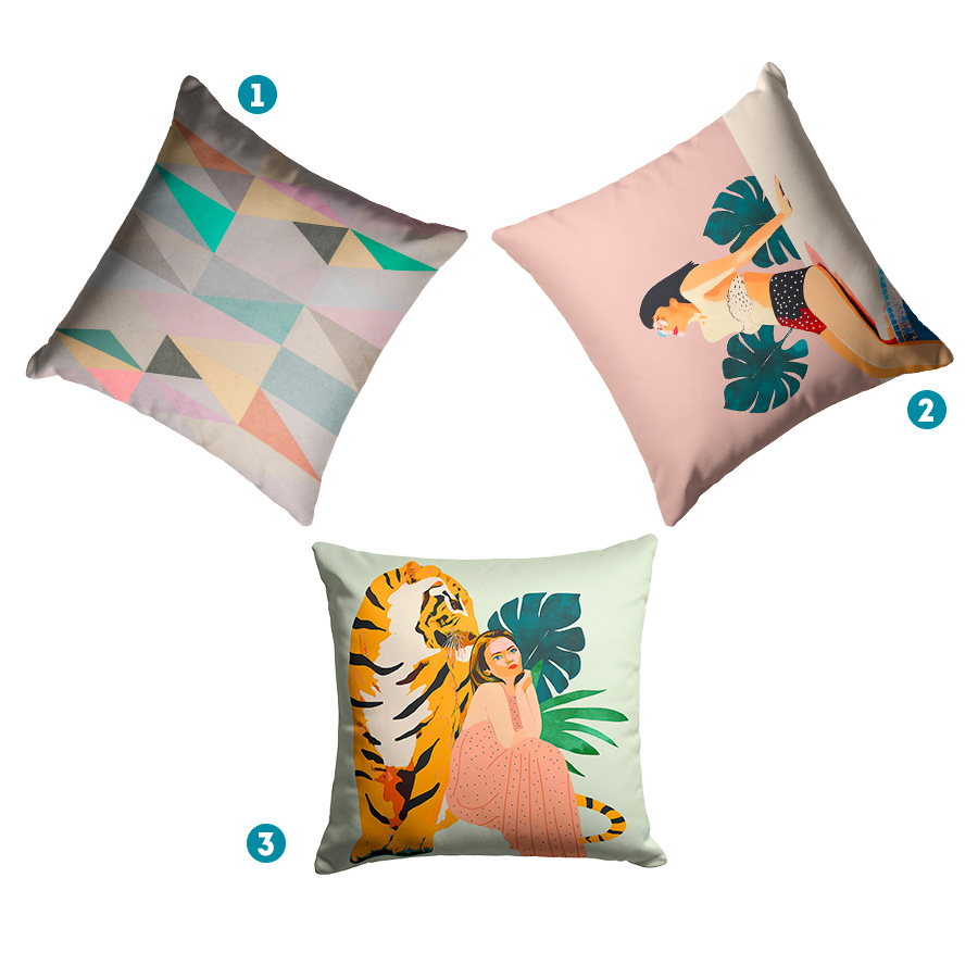Tres cojines. Uno con motivos geométricos de colores, otro con una mujer tomando sol en bikini y otro con un tigre y una mujer.