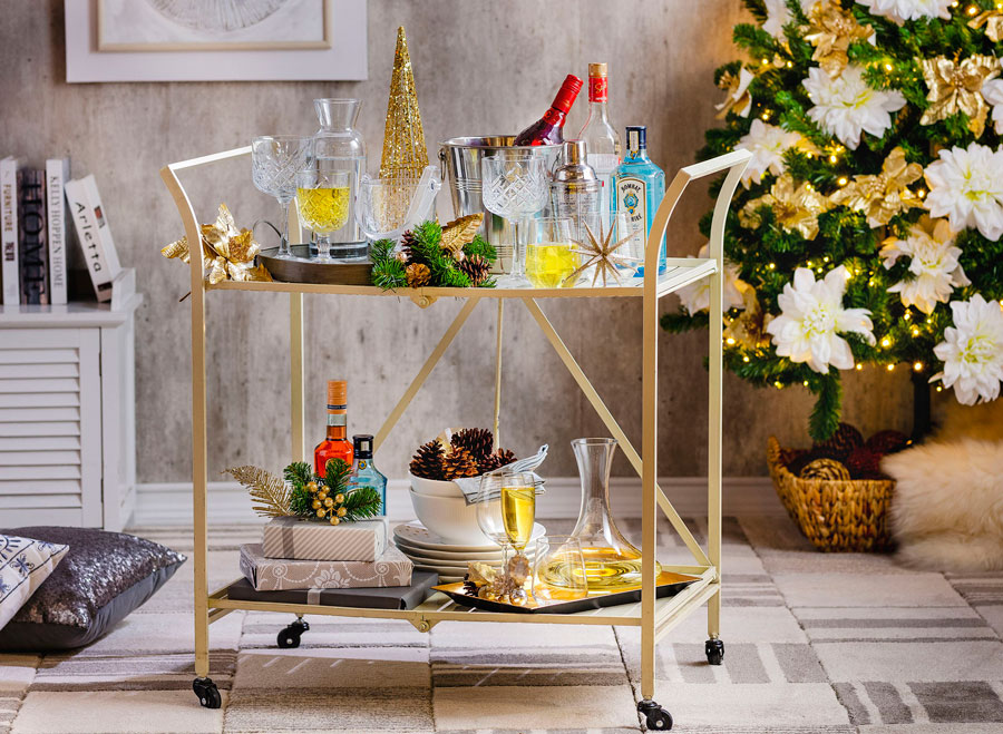 carrito bar plegable blanco decorado con copas, botellas, jarrones y bandejas, además de decoraciones navideñas