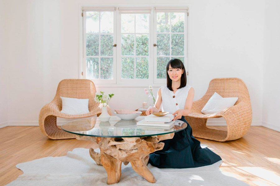 Marie Kondo posa en un living minimalista con dos sillones modernos de minbre y una mesa de centro de madera natural y vidrio.