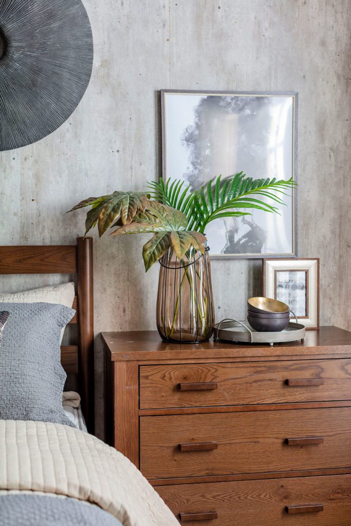 Detale de dormitorio, mueble velador con jarrón y hojas verdes decorativas