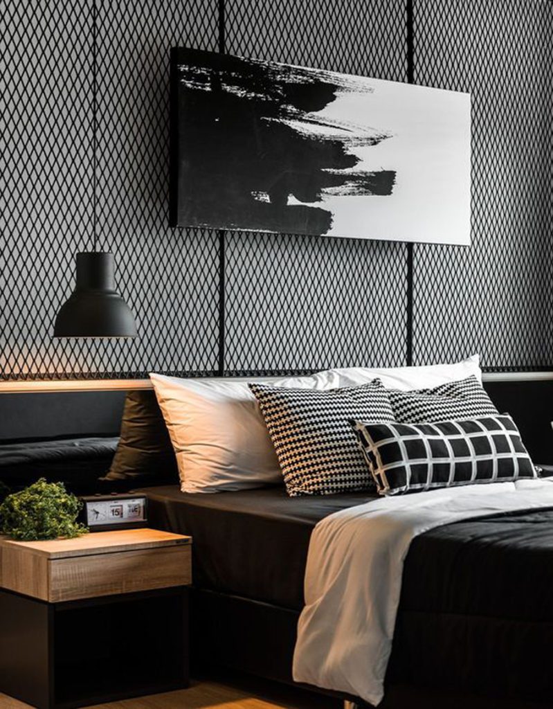 Dormitorio decorado en negro. Cama con sábanas negras, lámpara negra y un cuadro en blanco y negro