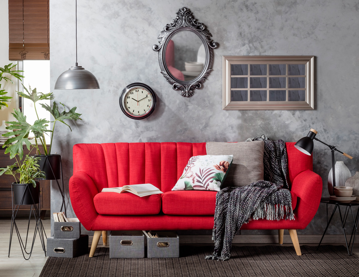 Living color gris con adornos metálicos en un color plata oscuro, destaca un sofá rojo intenso con patas de madera delgadas.