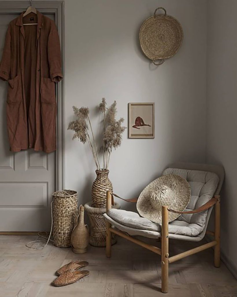 Rincón de un dormitorio con un sitial de mimbre y cojín en tono gris claro, acompañado de canastos en paredes y suelo del mismo material. Rincón de un dormitorio con un sitial de mimbre y cojín en tono gris claro, acompañado de canastos en paredes y suelo del mismo material.