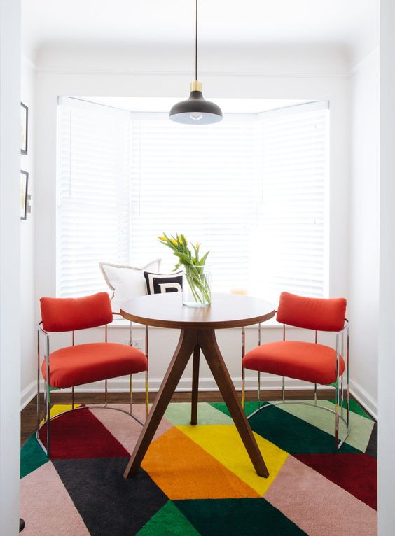 Comedor estilo maximal minimalism donde destaca una alfombra rosa con figuras geométricas.