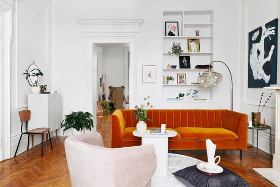 Living en tendencia maximal minimalism, donde destaca un sofá en color terracota y una poltrona rosa, ambos con líneas curvas.