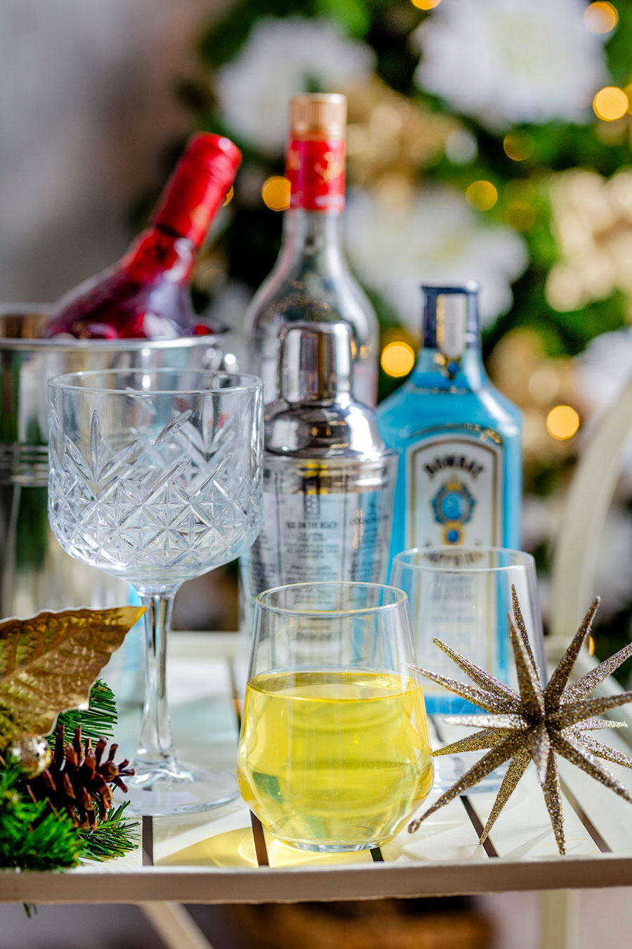 Bandeja con botellas de tragos, copas y vasos con bebidas y pequeños adornos navideños.