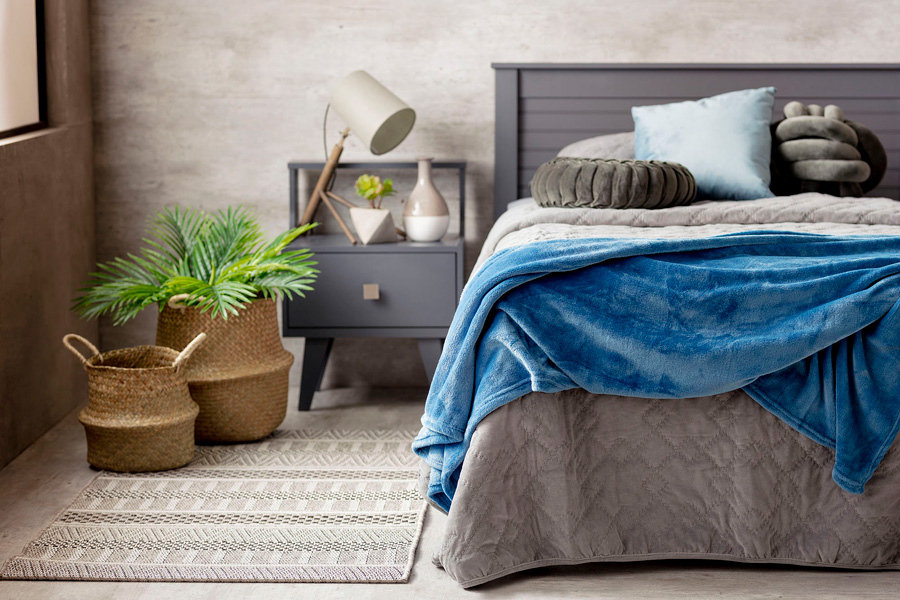 Dormitorio en colores grises con manta azul clásico color pantone 2020