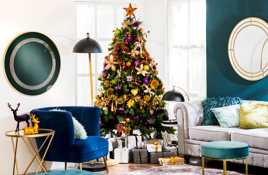 Living con sofá y poltrona azul clásico, con árbol de navidad en colores amarillo y morado.