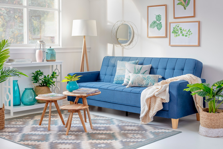 living con futón azul clásico color pantone 2020 y set de tres mesas con alfombra rombos