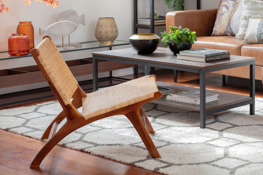 una poltrona de fibras naturales con base de madera en un living, frente a una mesa de centro y un sofá