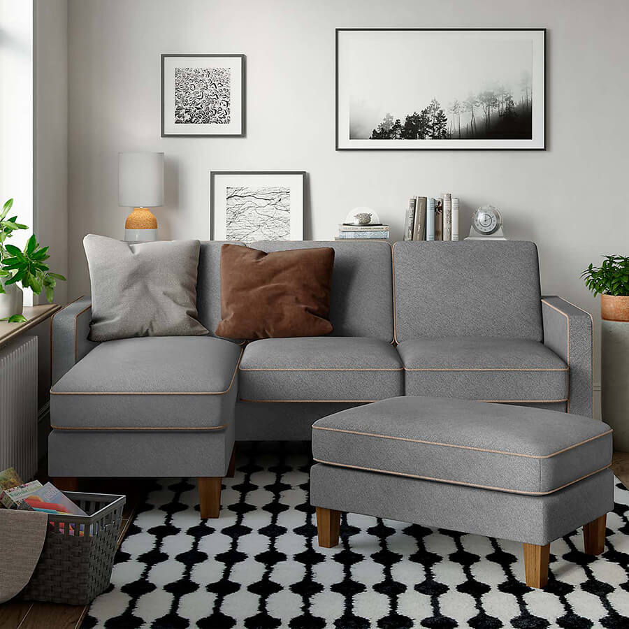 Living con un sofá gris de tres plazas en la esquina del espacio y sobre una alfombra blanco y negro.