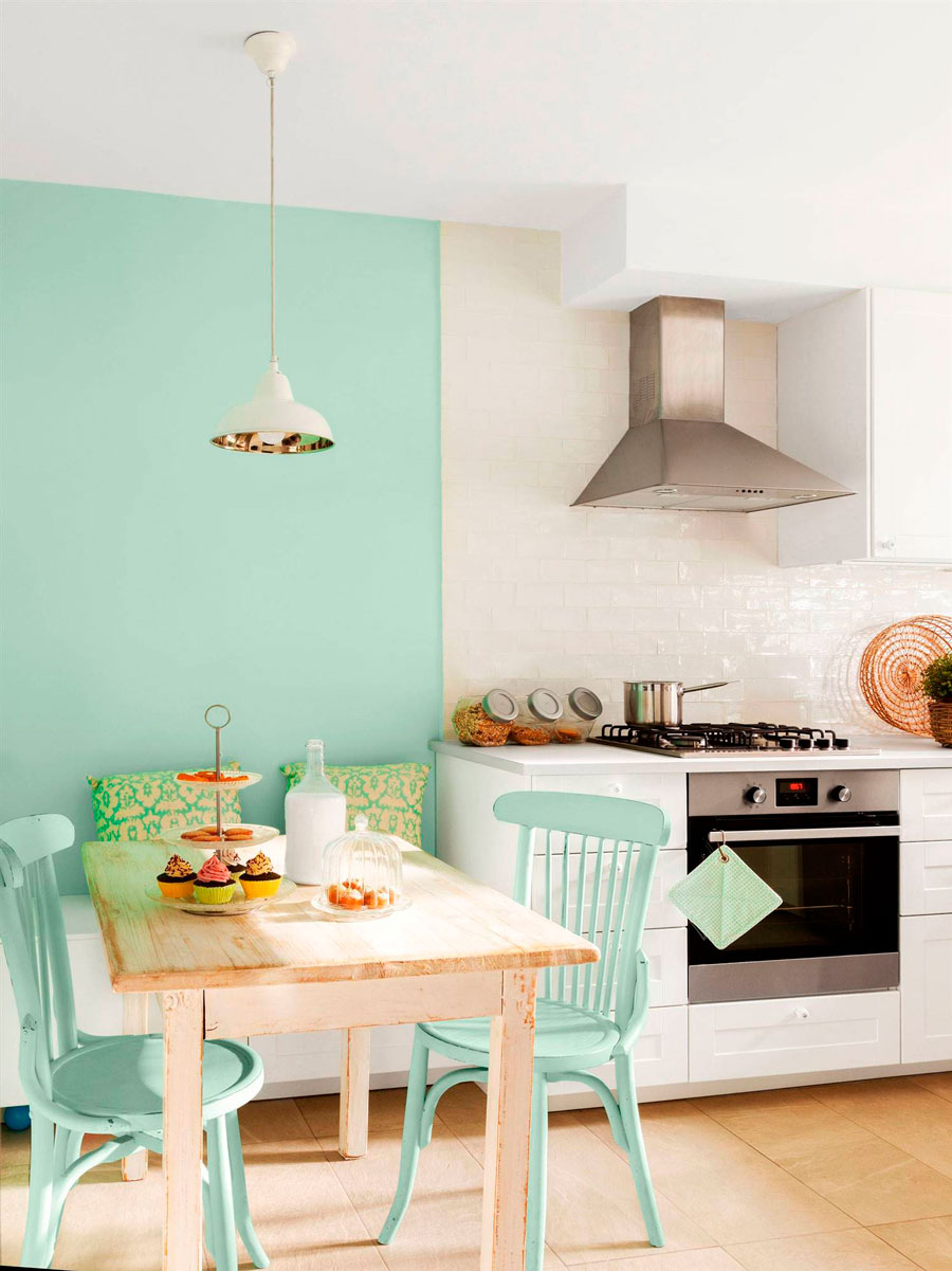 Cocina con una parte de la pared pintada con pintura tizada color menta, dos sillas pintadas con el mismo color y una mesa de madera.