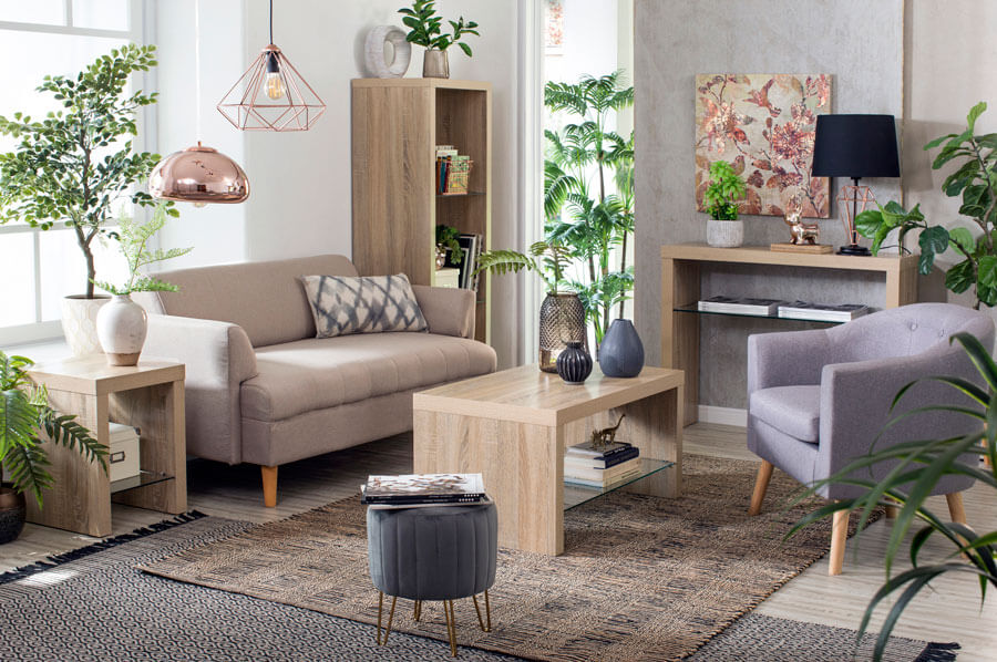 Living con sofá beige, pouf gris oscuro y poltrona gris claro, una mesa de centro, repisa, arrimo y mesa lateral de madera, y dos alfombras marrón y gris.