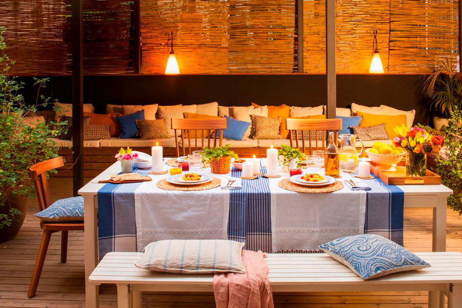 Terraza con dos ambientes: comedor y living. Sobre el comedor hay dos lámparas colgantes simples.