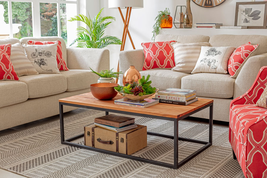 un living con sofás de color claro con cojines decorativos de diseño y una mesa de centro con cubierta de madera y base de metal
