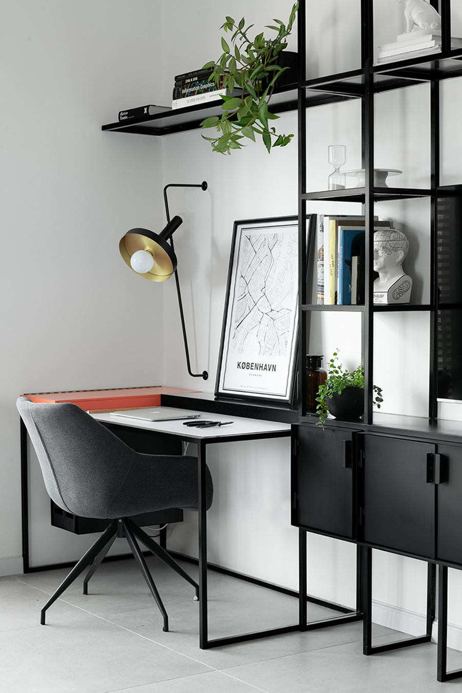 Escritorio de estilo ejecutivo urbano Escritorio en el que predominan los colores blanco y negro. Muebles de metal negro como escritorio y estanterías, una lámpara del mismo color, una silla gris oscura y un cuadro blanco y negro.