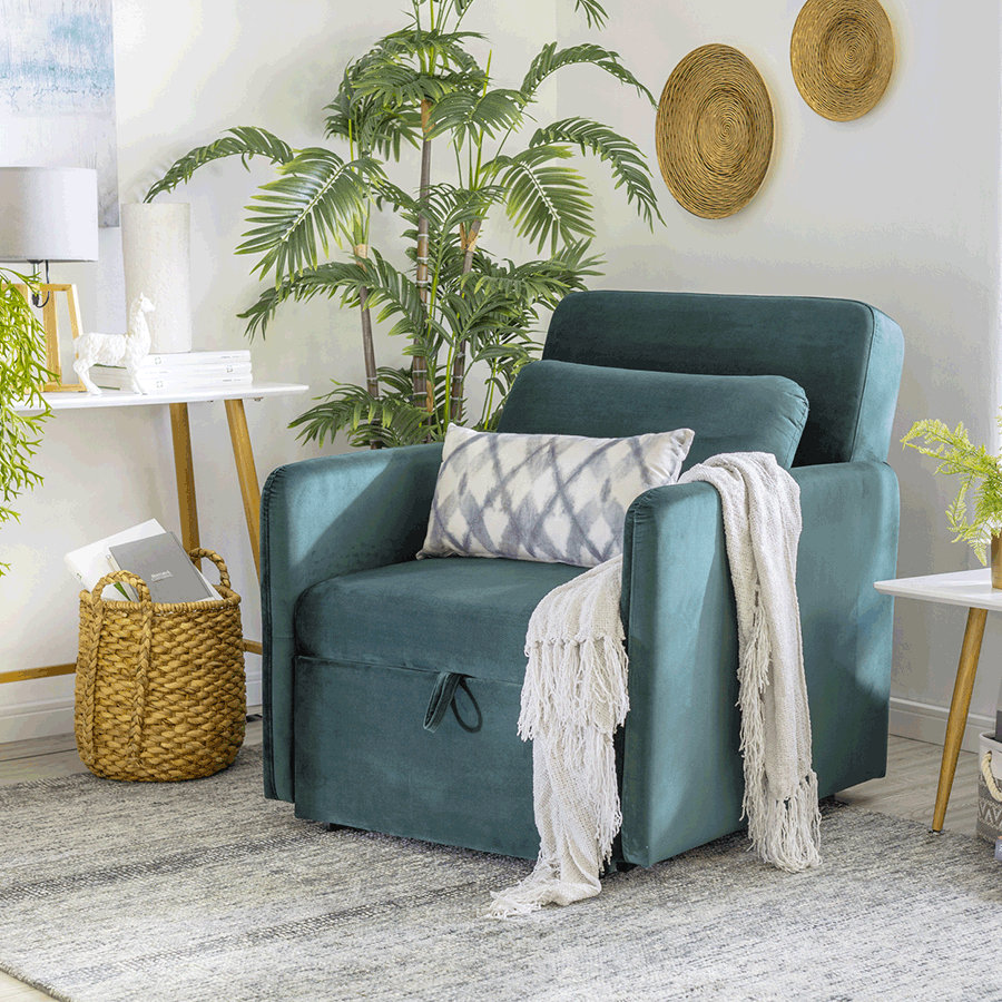 Gif de una poltrona verde que se abre para formar una cama estilo chaise lounge. Tiene un cojín blanco con patrones azules y una manta blanca. Está sobre una alfombra gris y a sus lados hay un arrimo y una mesa lateral.