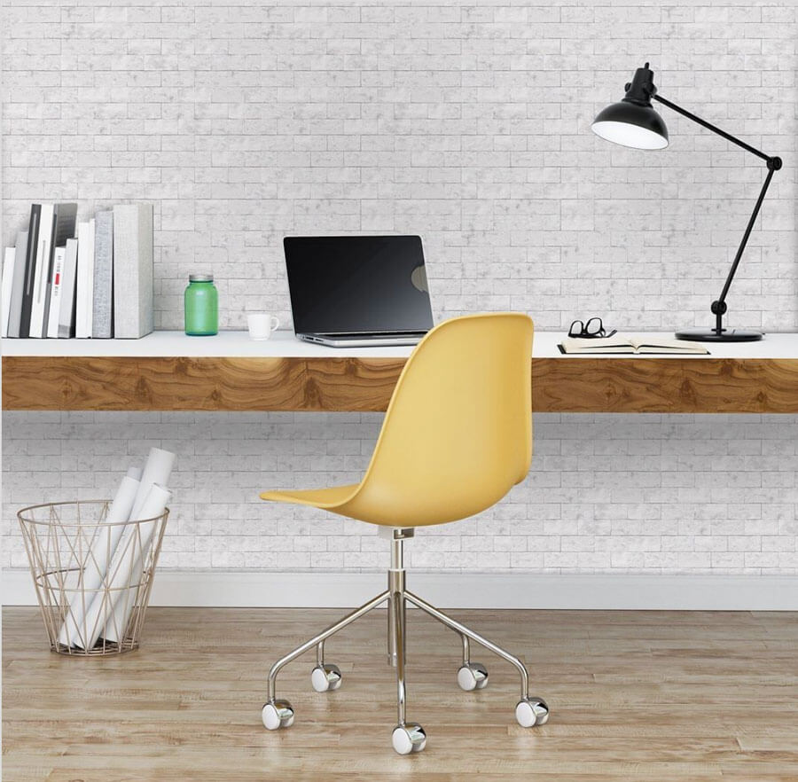 Oficina con pared de fibrocemento línea piedra simplísima, el escritorio está montado sobre la pared y acompañado por una silla de escritorio amarilla.