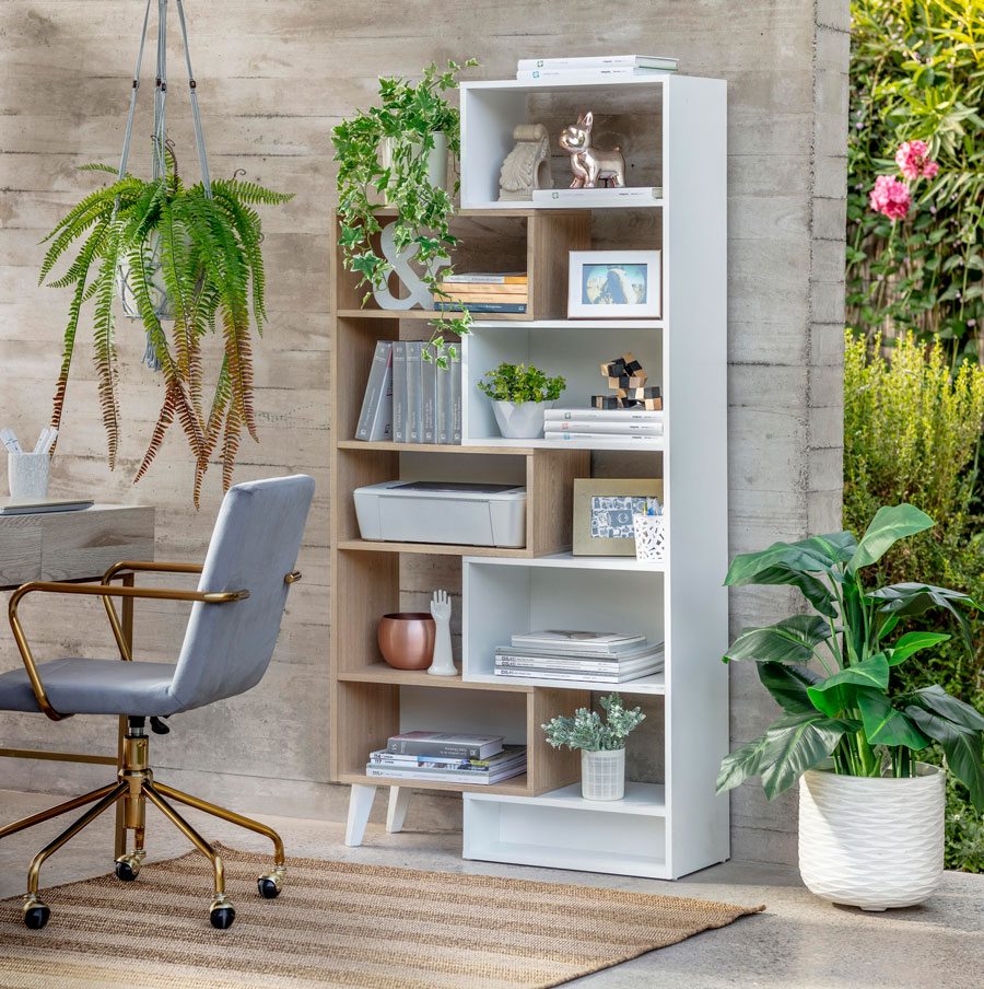 Home office en un espacio al aire libre, con un librero vertical grande, plantas y una silla de escritorio gris con dorado