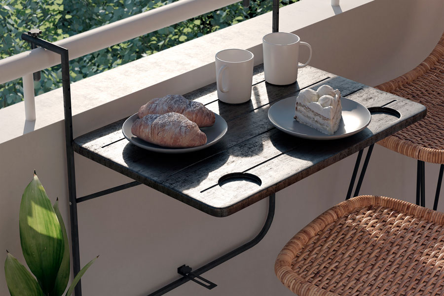 Una mesa plegable negra puesta en un balcón con croissant, pastel y 2 tazas de café