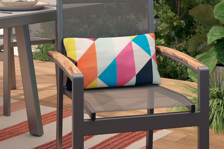 Una silla para terraza de metal con detalles de madera con un cojín con patrones geométricos multicolor