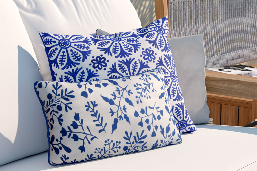 Una imagen de un sofá con dos cojines azules y blancos. El sofá es de color gris claro y tiene un diseño moderno.