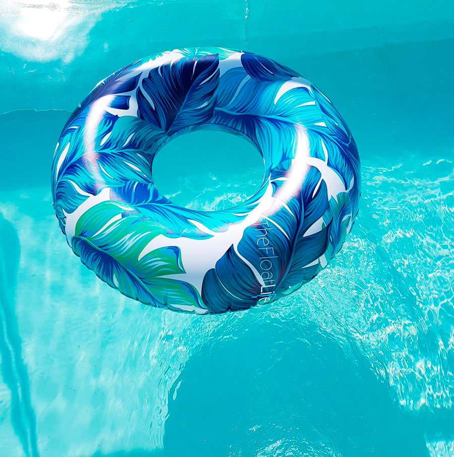 El flotador con forma de dona, y patrones de plantas en verdes y celestes, también sirve como objeto decorativo de la piscina.