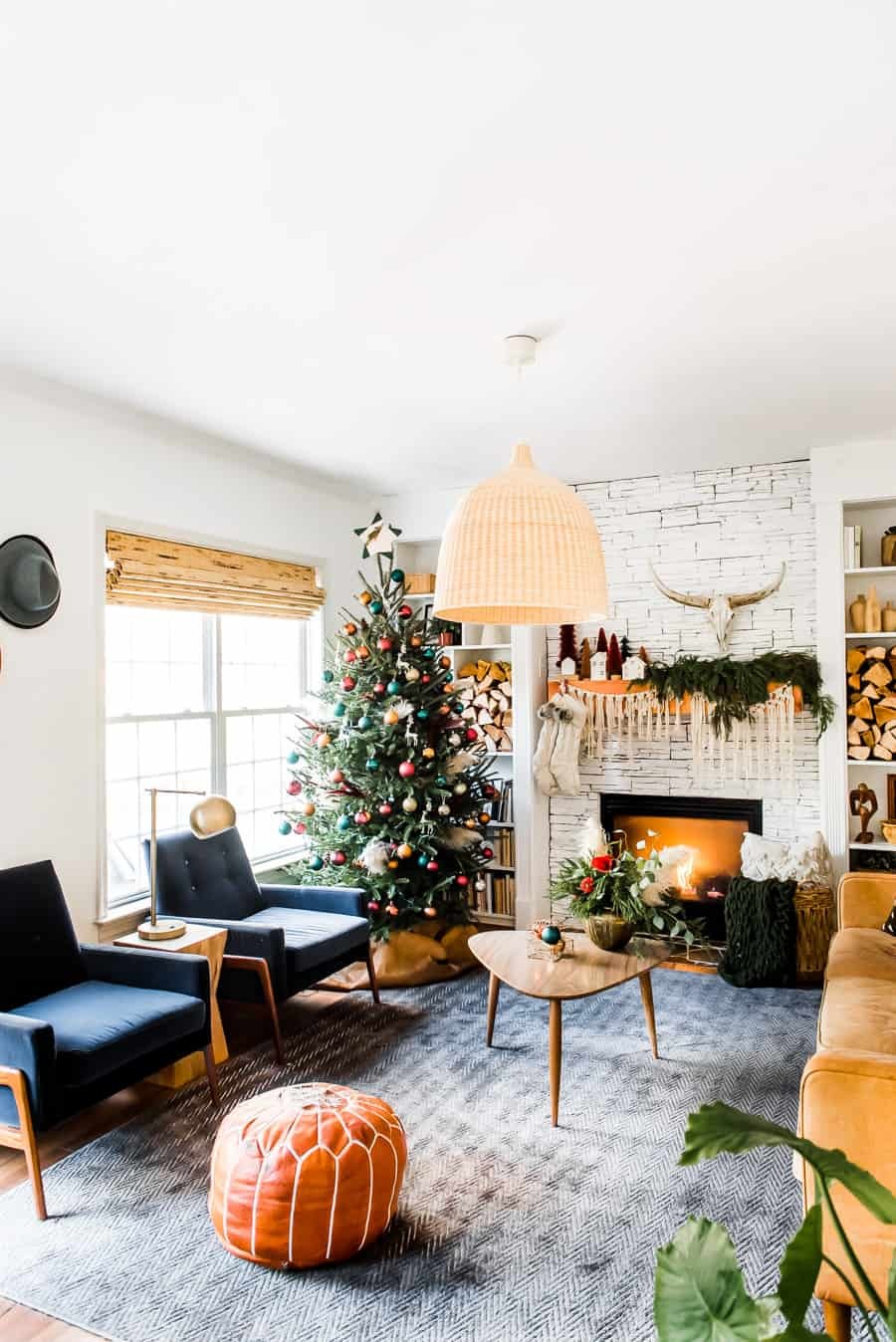 Una sala de estar con paredes en tonos blanco y beige refleja la paleta de colores de la decoración estilo boho. Incluye decoraciones navideñas en dorado y cobre junto a muebles en tonos terracota, anaranjados y azules.