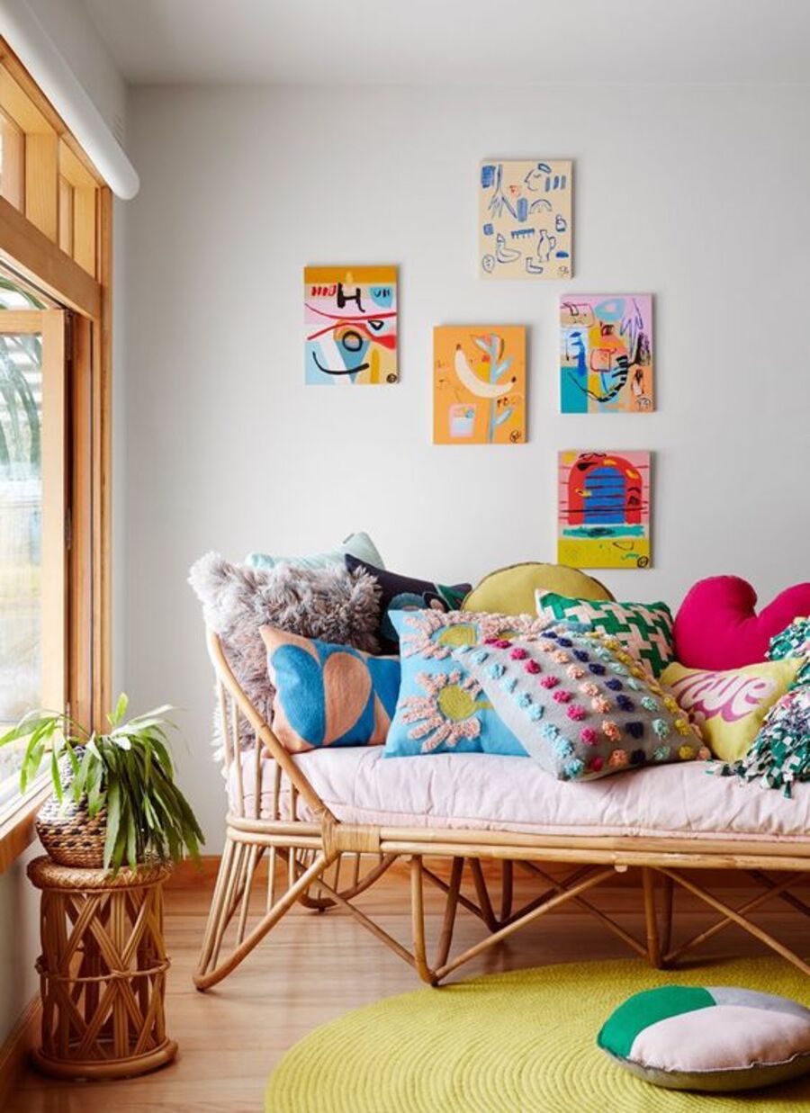 Un sofá hecho de mimbre en un living y decorado con varios colores de distintos colores y patrones.