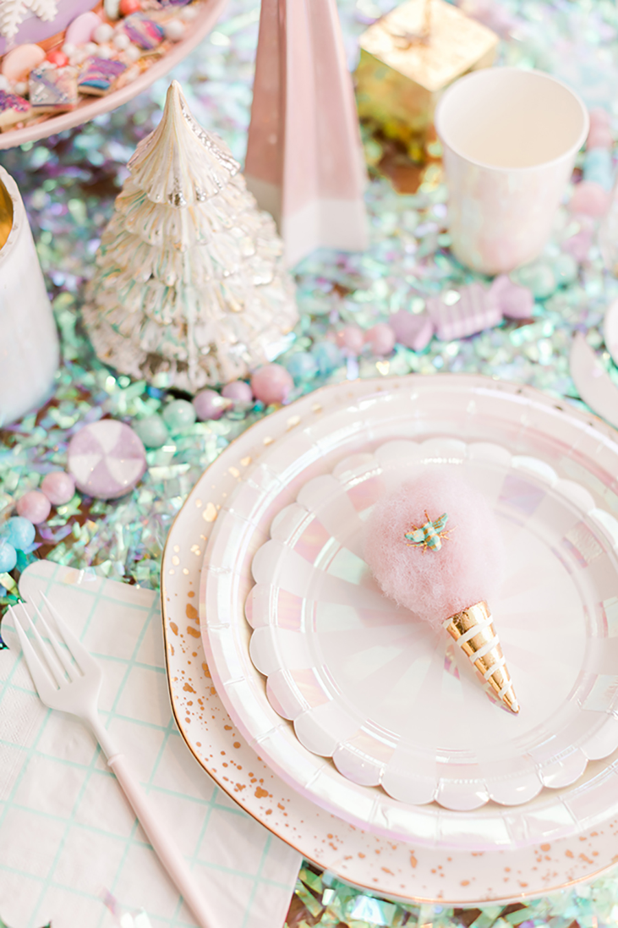 Agrega un toque romántico de Navidad a tu mesa para la cena de Noche Buena, como en la fotografía con platos colores pasteles y muchos adornos.