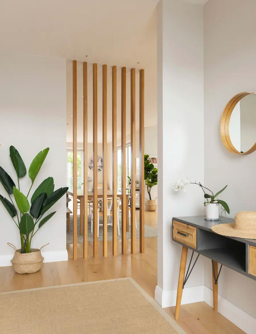 Junquillos de madera instalados verticalmente separando el área del comedor con el espacio de recepción de un hogar.
