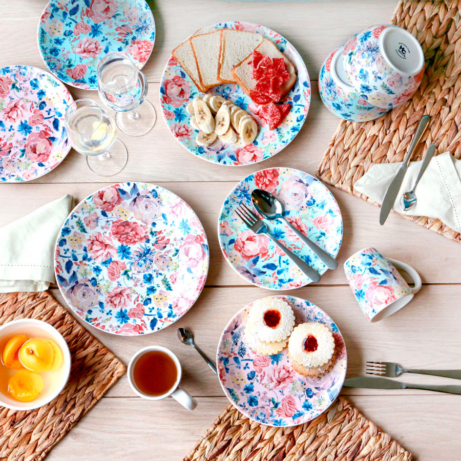 Una mesa puesta con muchos platos con diseño de flores, que combinan.
