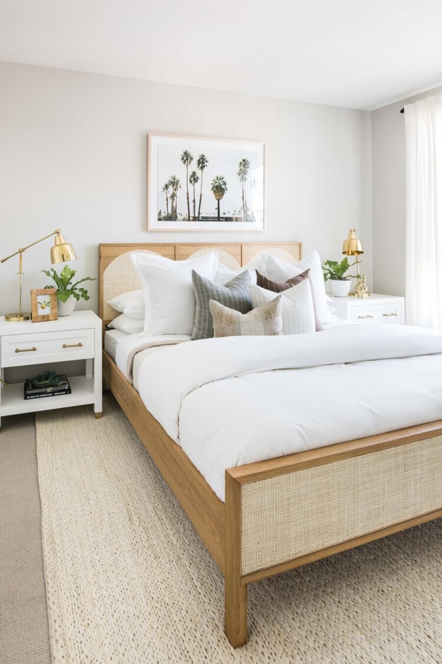 Dormitorio estilo boho chic, con una cama de madera y respaldo de fibras naturales, veladores blancos y lámparas de mesa dorados.