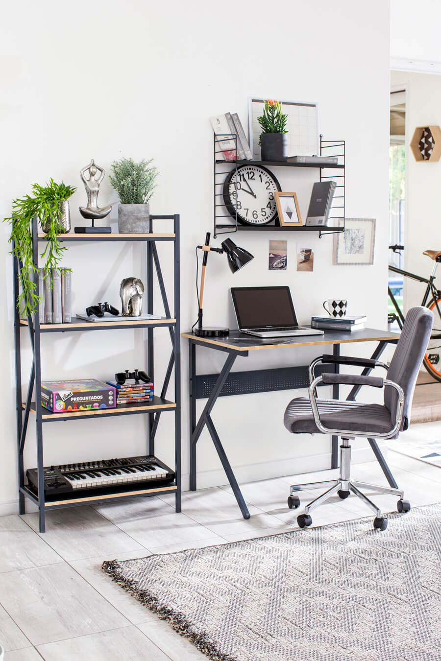 Zona de trabajo estilo industrial con un escritorio negro combinado con un estante del mismo estilo. Sobre el escritorio hay una repisa flotante negra y frente al escritorio hay una silla de oficina negra sobre una alfombra gris.