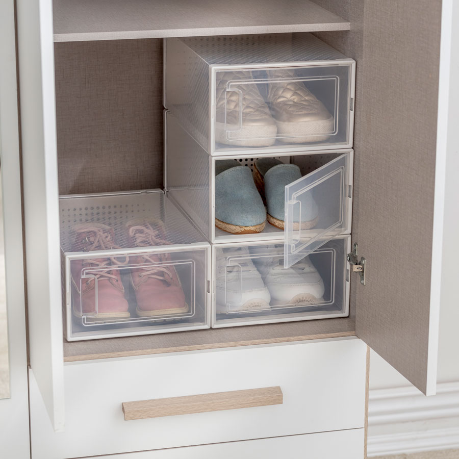 4 cajas organizadoras plásticas para guardar los zapatos. Están ubicadas dentro de un clóset blanco, cuyas puertas están abiertas para mostrar las cajas.