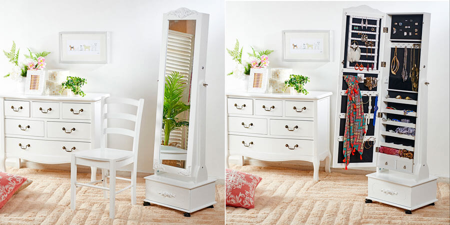Mueble joyero blanco con un espejo en la parte frontal de la puerta, ubicado sobre una alfombra color crema y al lado de una cómoda blanca estilo clásico con manijas negras.