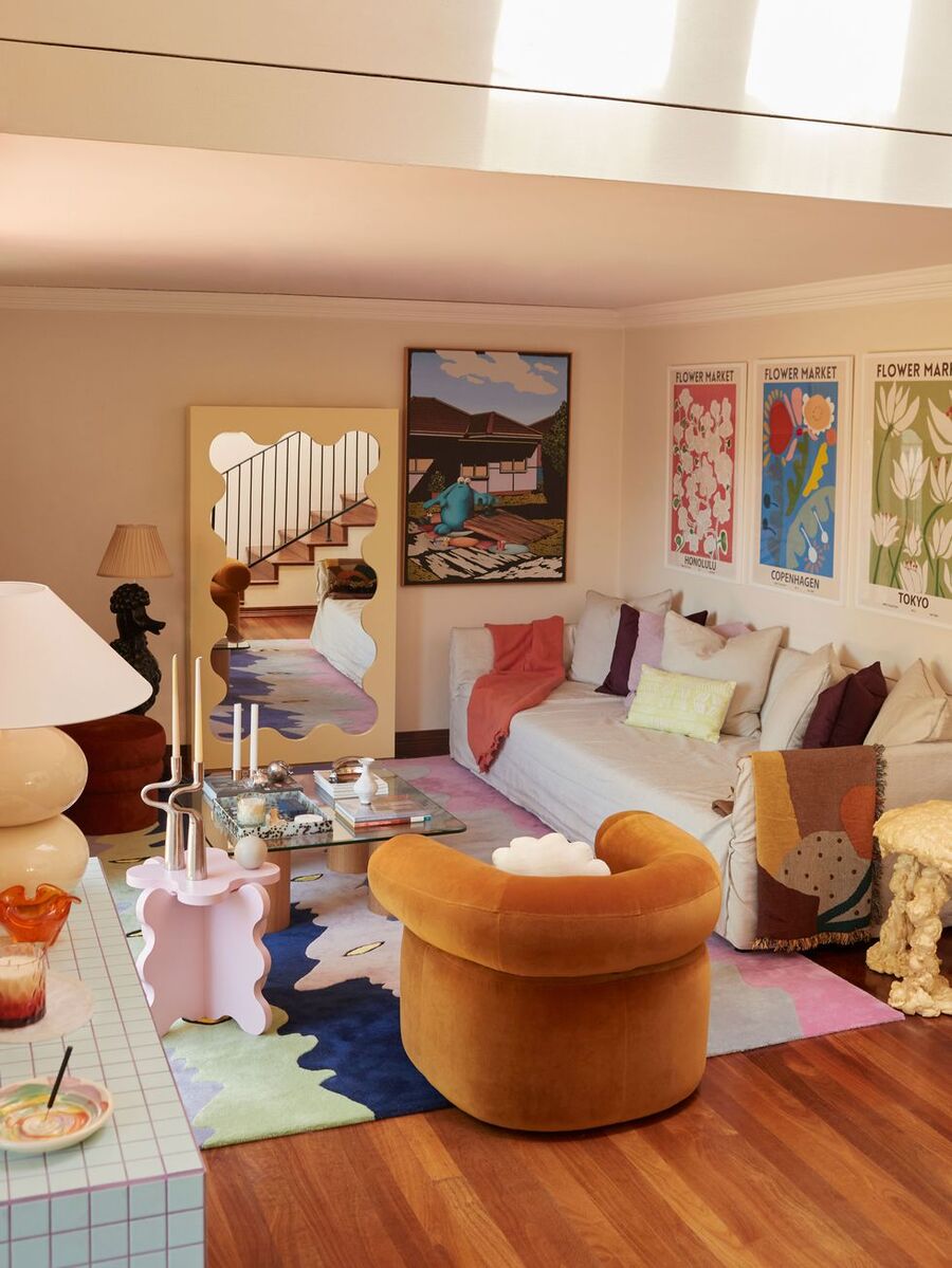 Living y sala de estar de estilo Y2K, con muebles y adornos de formas curvas, colores pasteles y cuadros, alfombra y cojines coloridos.