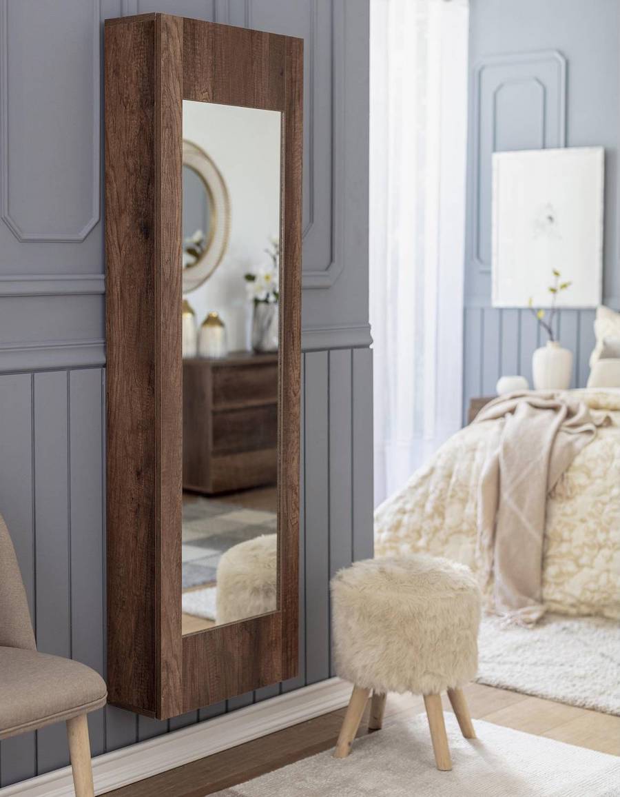 Dormitorio de estilo clásico con paredes grises con molduras, piso de madera y alfombras blancas. En uno de los muros está instalado un mueble para guardar zapatos angosto de madera oscura y espejo en su puerta. 