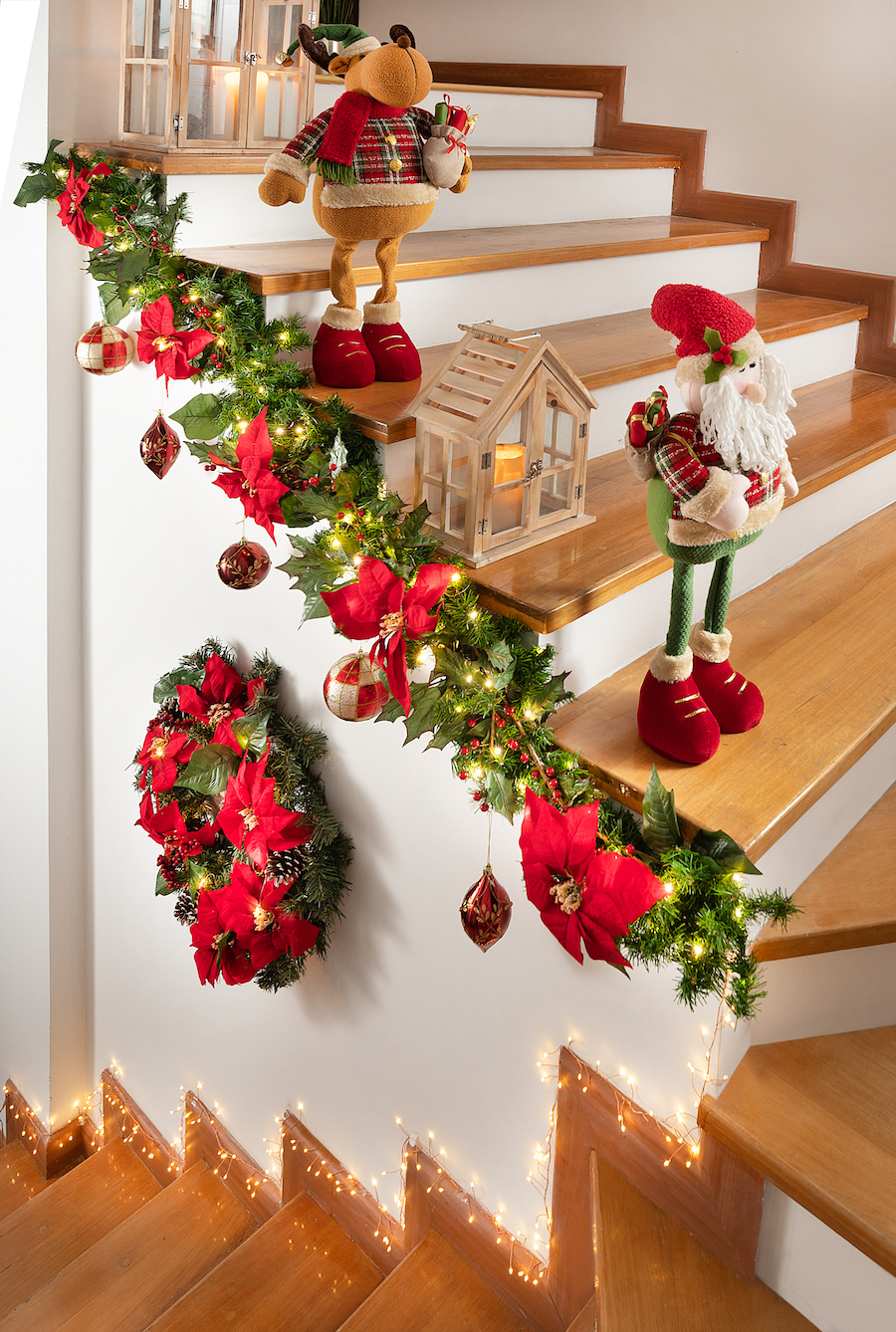 Escalera interior de una casa adornada con luces, guirnaldas y adornos navideños.
