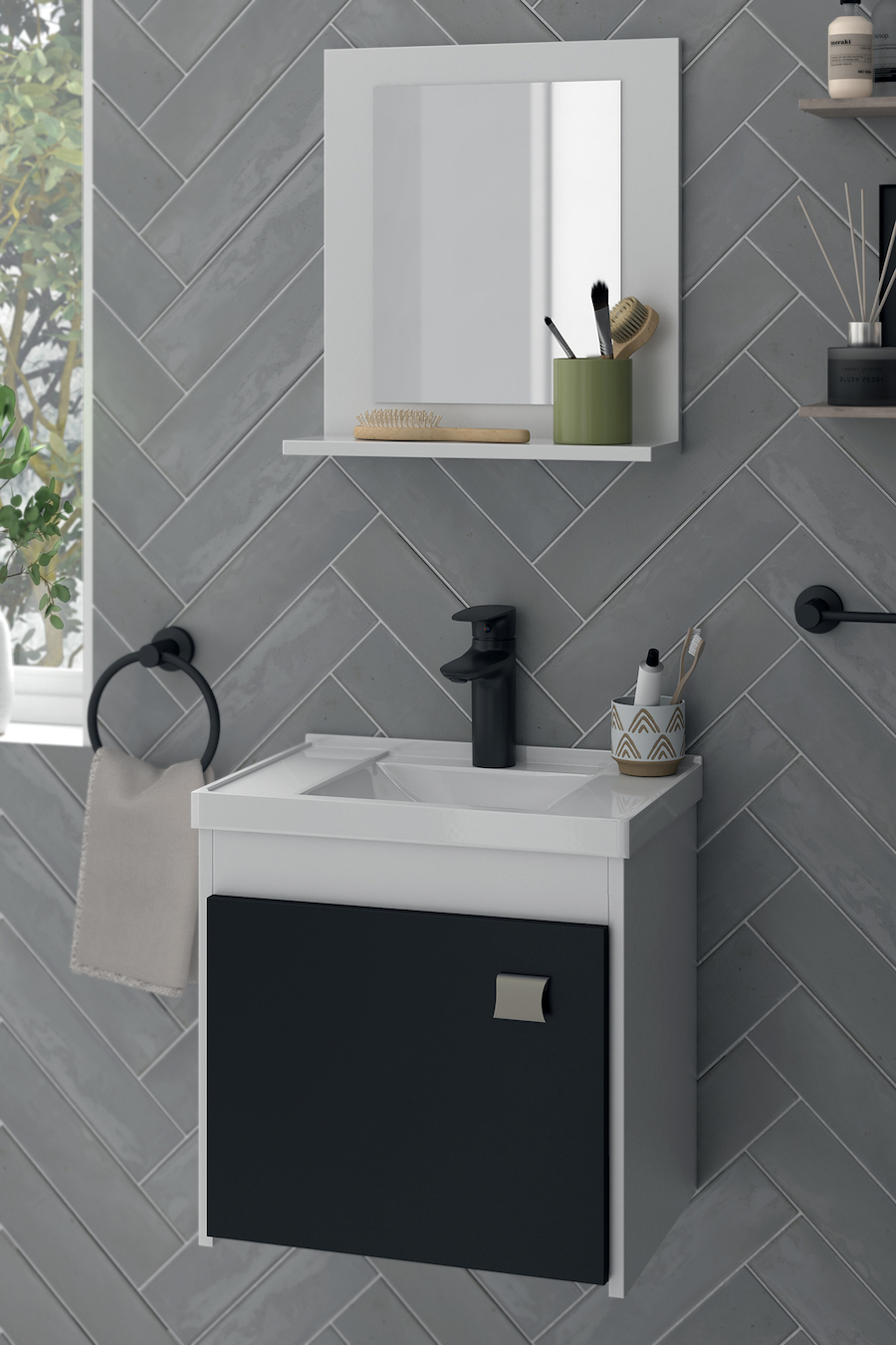 Detalle de un baño con cerámicos grises, vanitorio blanco con puerta negra, grifería negra y espejo con marco y repisa blanca.