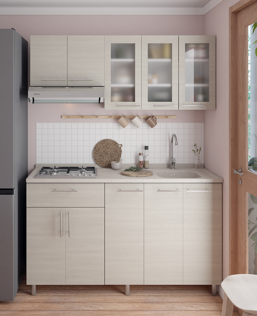 Cocina pequeña con muebles de madera muy clara, manillas plateadas, paredes rosadas y cerámicos blancos.