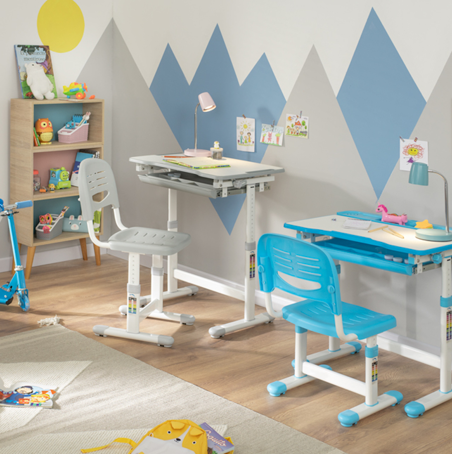 Dormitorio infantil con 2 escritorios ajustables, un estante con juguetes y libros ordenados y una gran alfombra con algunos objetos sobre ella.